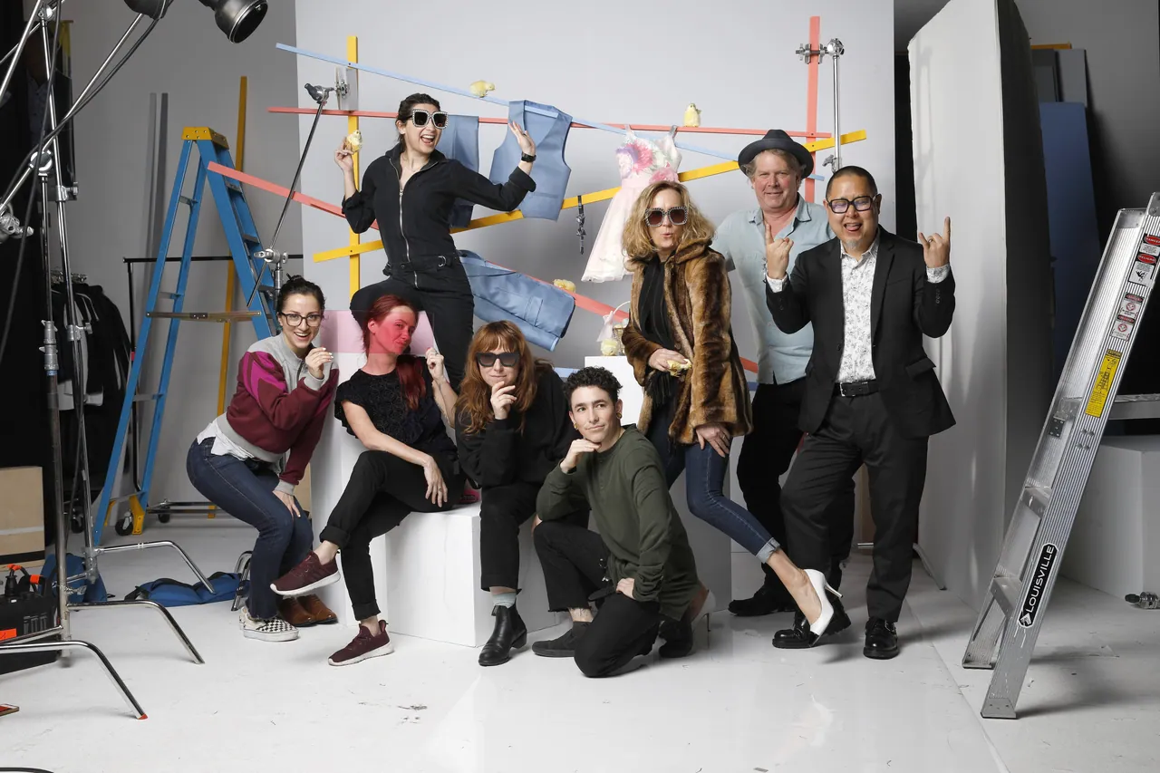 The creative team on set at a K&G photo shoot, posing with hats, books and props in front of studio lights