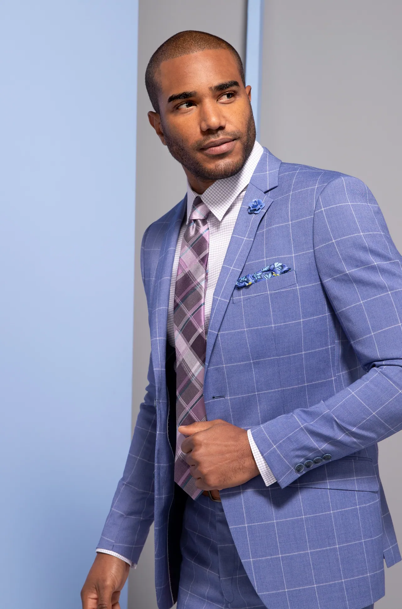 Model in a blue suit against powder blue and coral panels