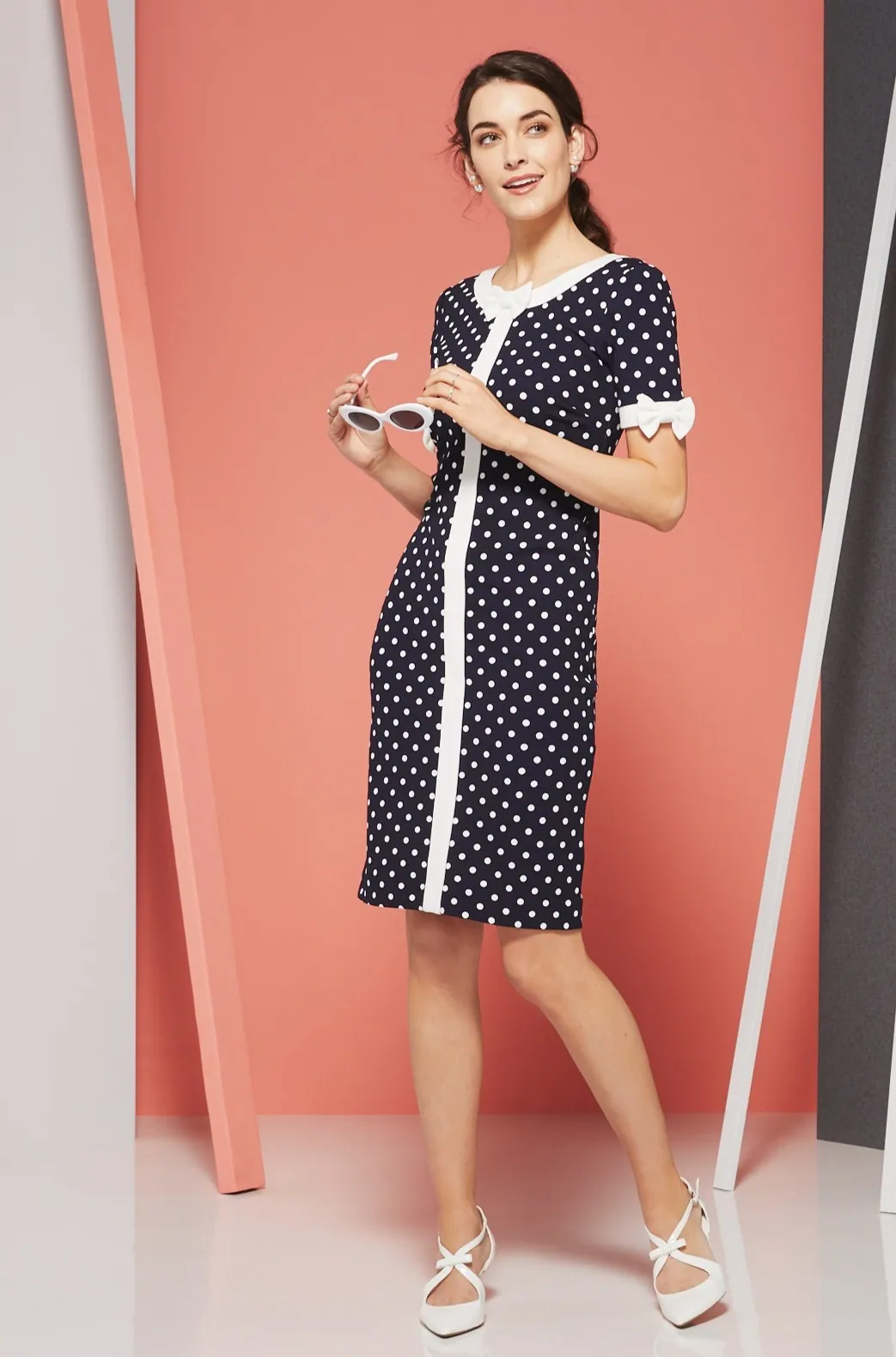 Model in a navy and white dress beside coral and gray panels