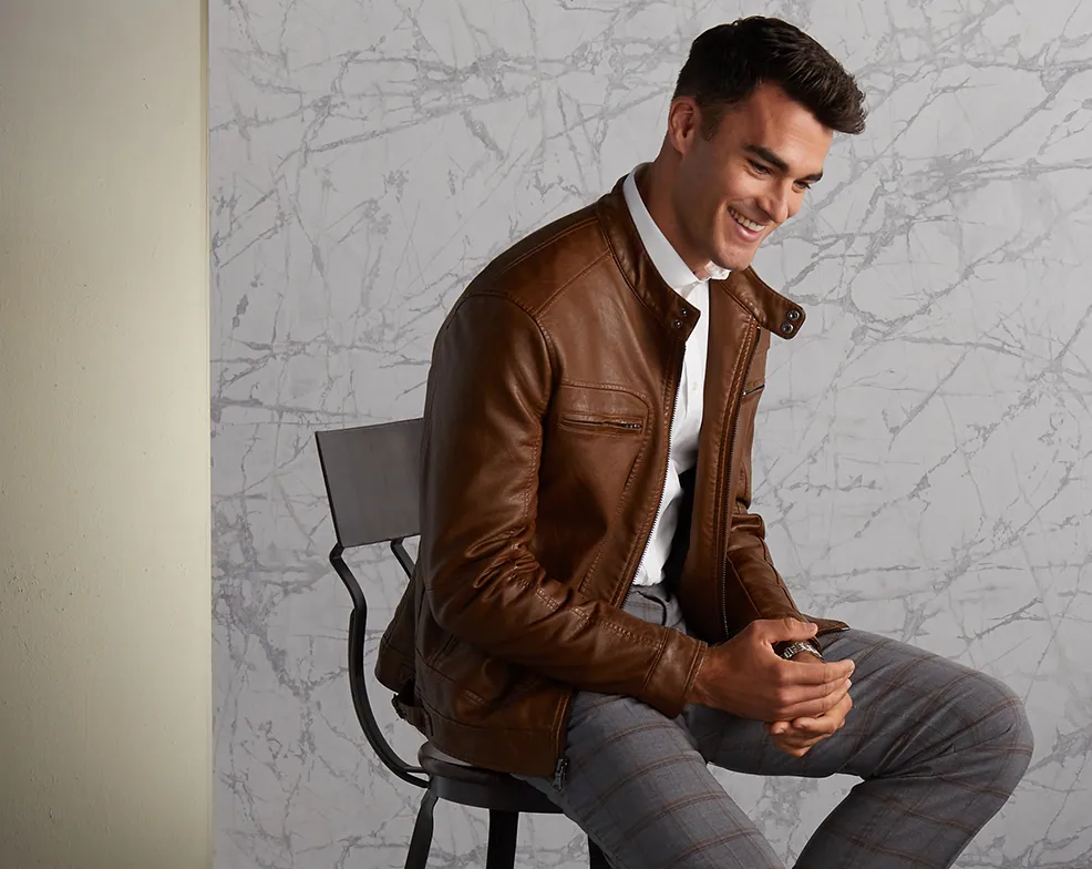 Model in a brown leather jacket seated on a stool