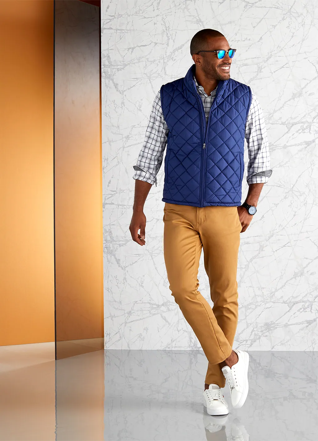 Model in a quilted navy vest and khakis on an orange set