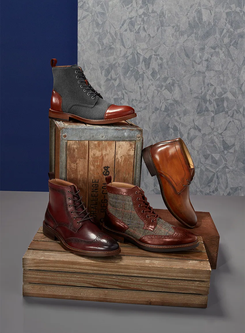 Still life of men’s boots on a wooden stump