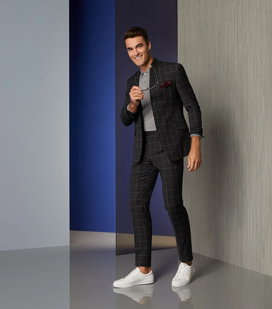 Model in a dark suit against a deep blue wall