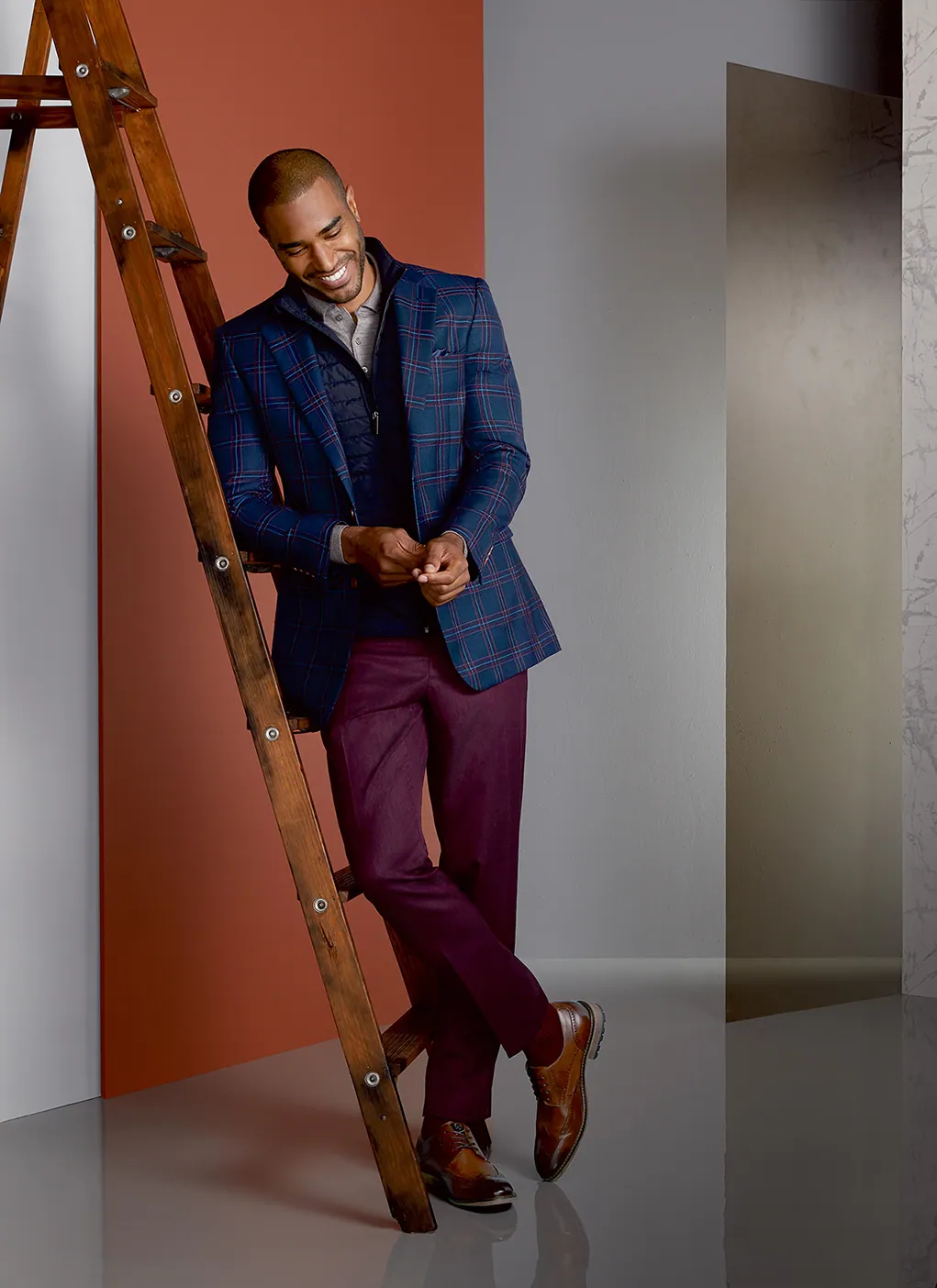 Model in a navy topcoat on a wooden ladder