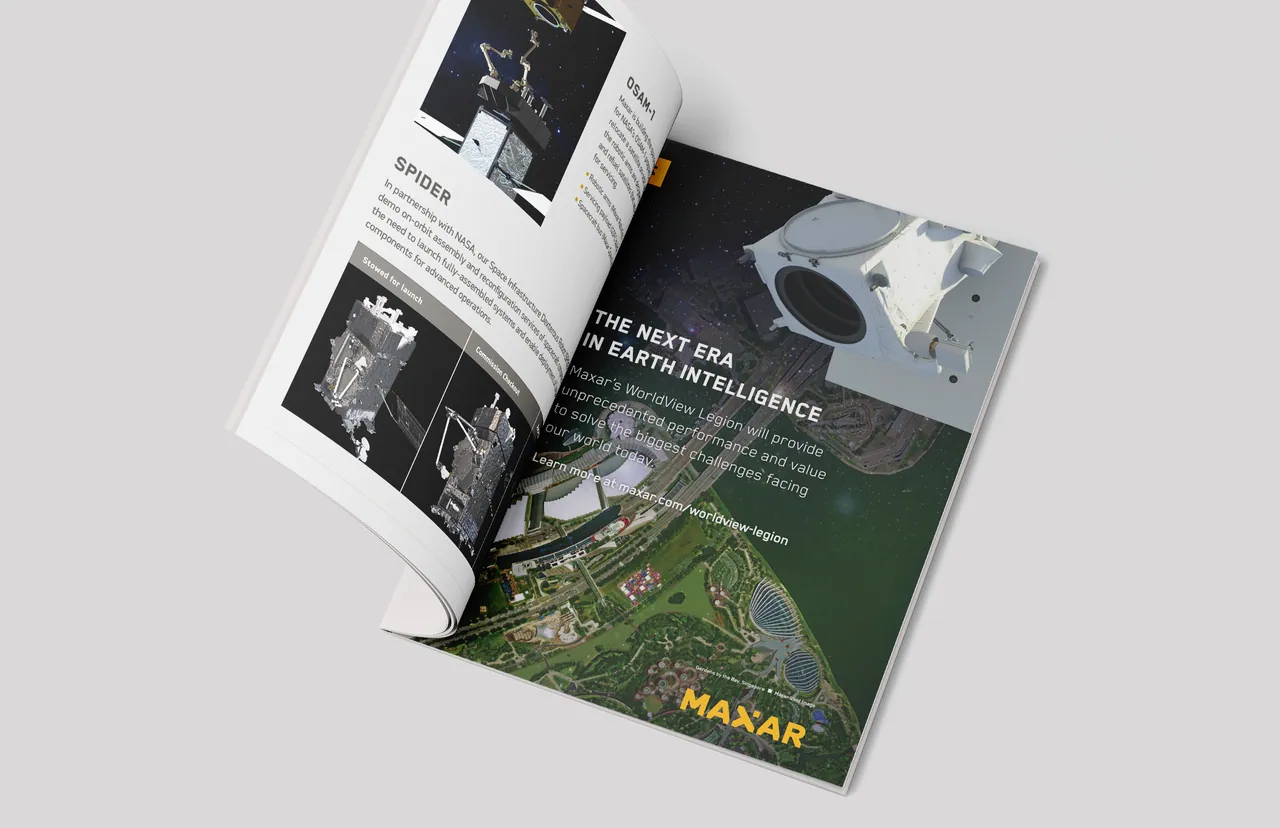 Printed magazine ad for Maxar at GSTC 2023, open on a light gray surface