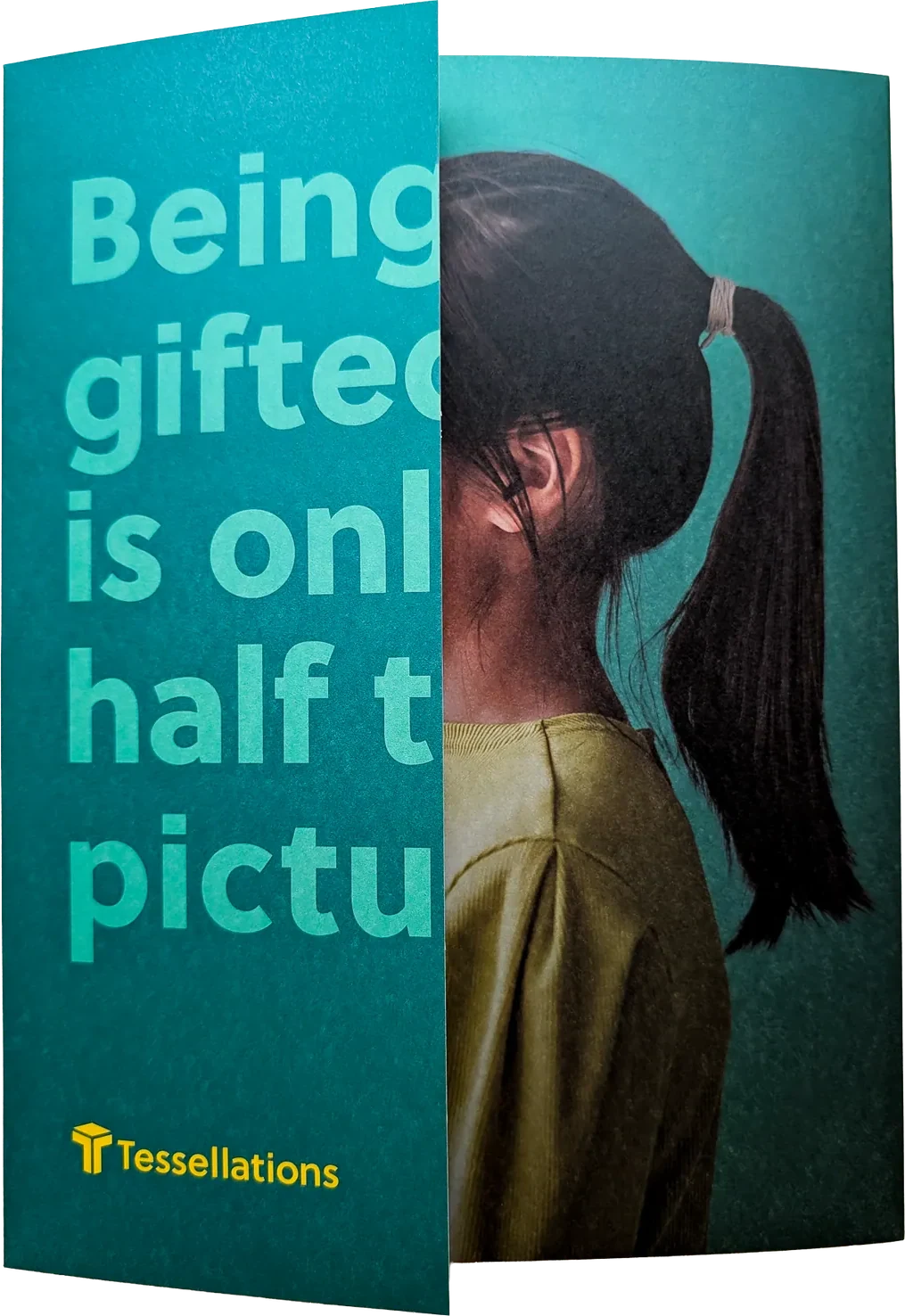 The printed folder front, photographed: Being gifted is only half the picture in green type over a girl’s profile, with the Tessellations logo