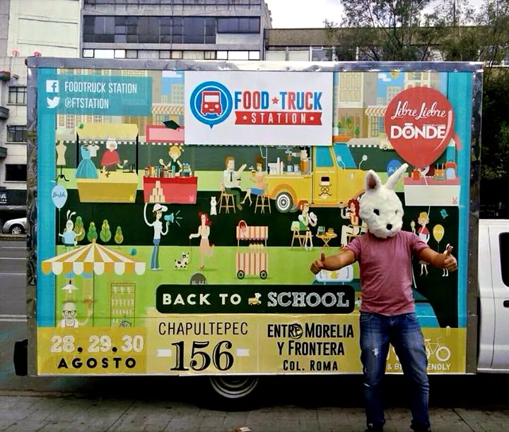A person in a rabbit mask standing beside the wrapped truck